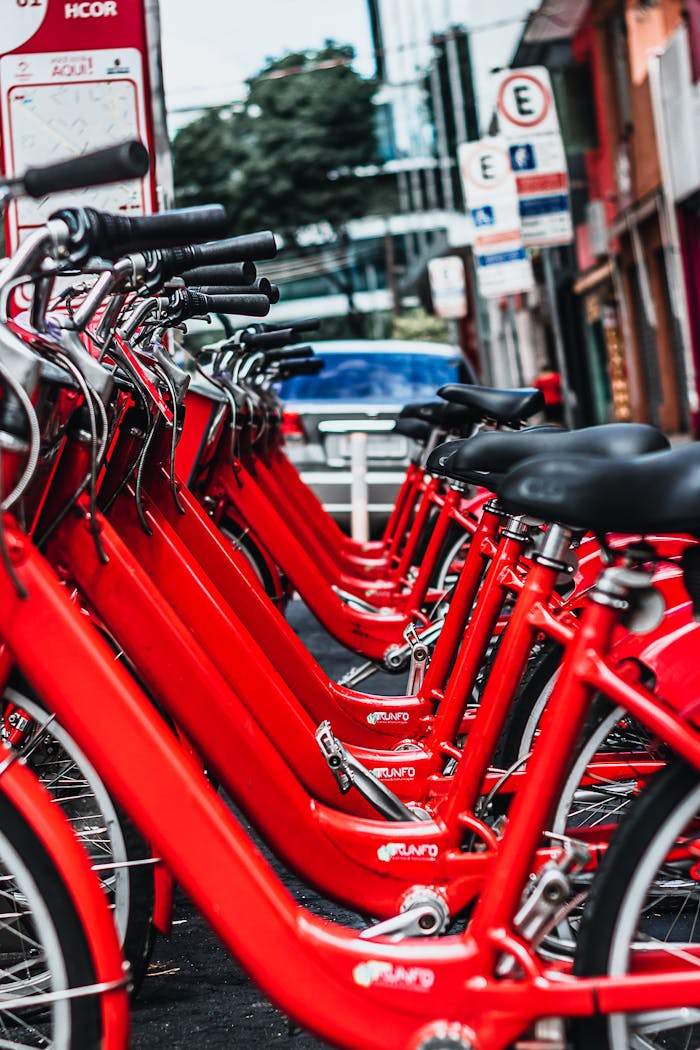 Row of bright red bicycles parked on a bustling street in Sé, São Paulo, Brazil.